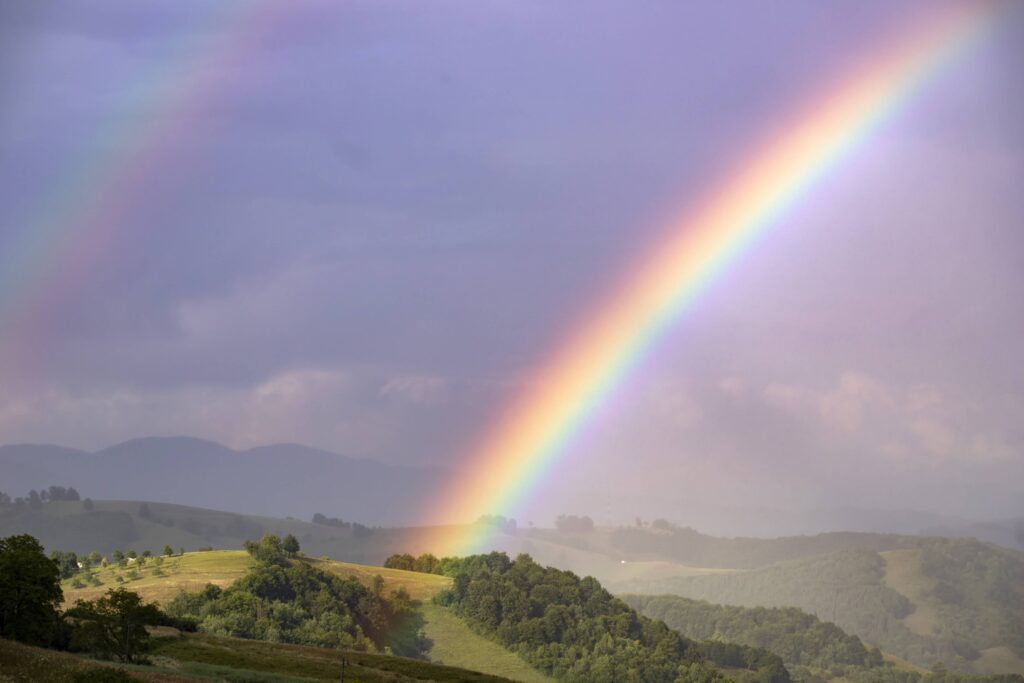 Rainbow over a green summer hills and mountains.