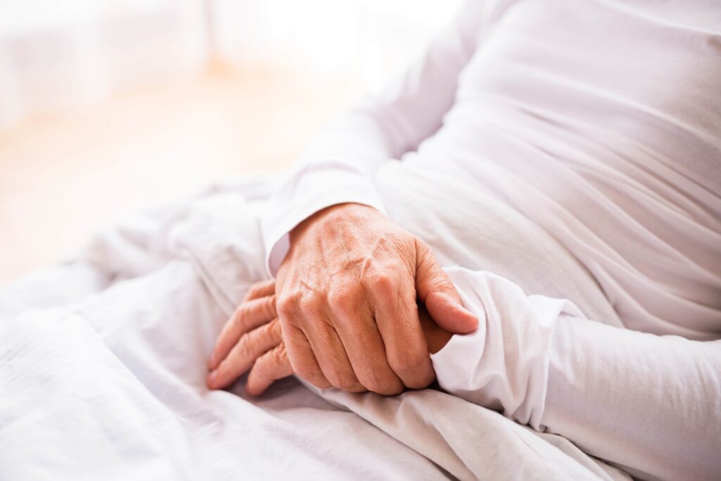 Unrecognizable senior man lying in adjustable bed at home.